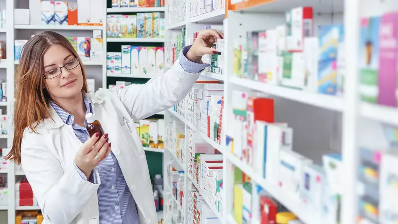 woman pharmacist holding bottle of medicine
